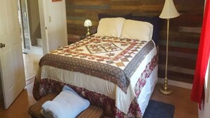 Une chambre à coucher avec un lit, une table de chevet, une lampe et une porte.