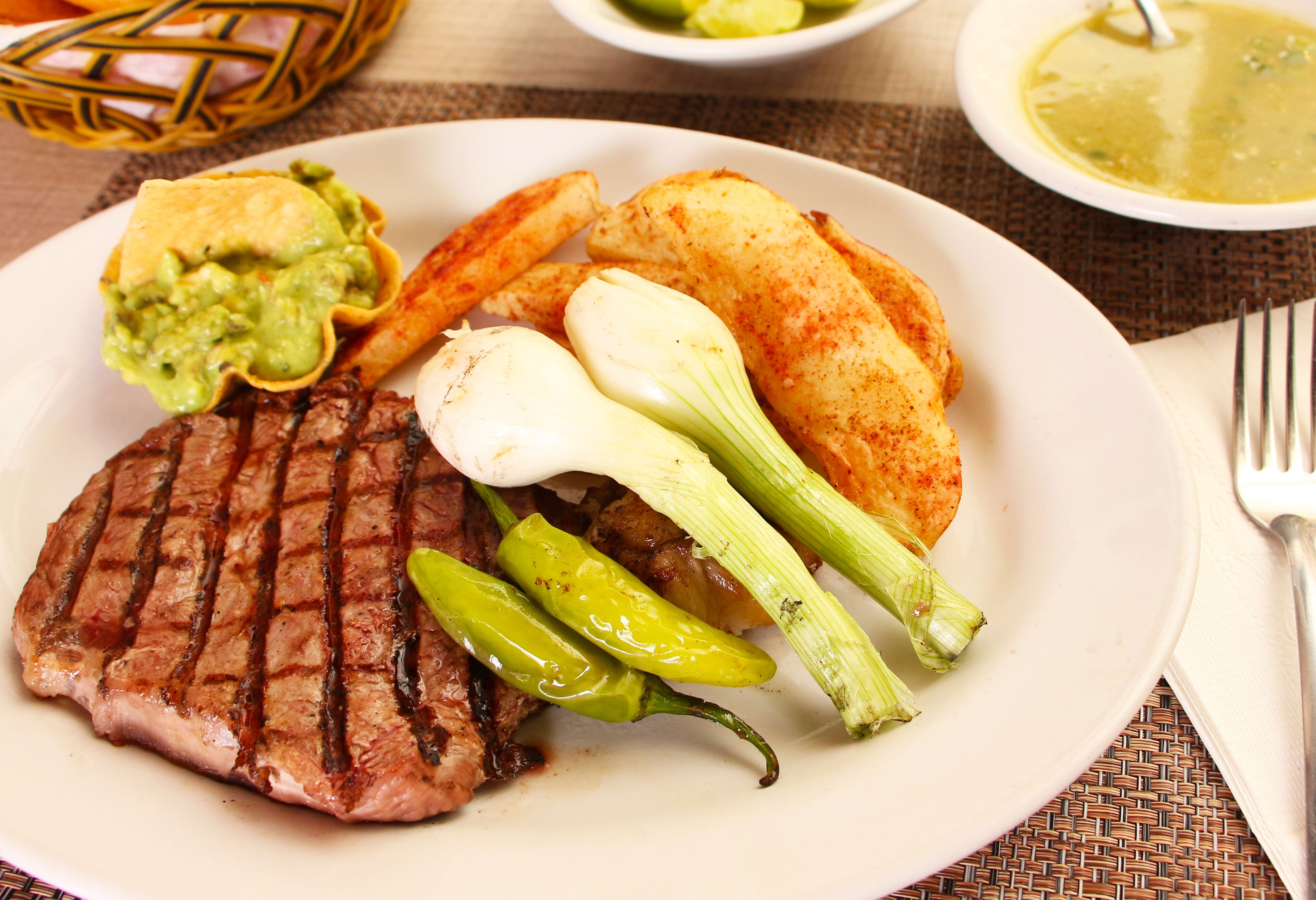 Plat de menjar amb entrecot a la planxa, guacamole, patates rostides i verdura.