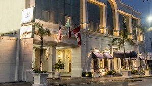 Un hotel con una entrada imponente, ventanas amplias y banderas.