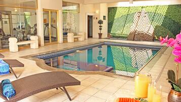 Een zwembadgedeelte met ligbedden, een jacuzzi en een muur met een ontwerp van groene bladeren.