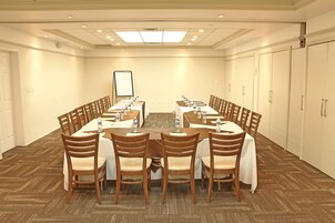 Una sala de conferencias con una gran mesa ovalada, sillas de madera y una pizarra al frente.