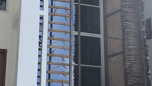 Um edifício com uma janela grande, uma escada de madeira e uma parede com textura.
