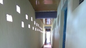A long, narrow hallway with a red carpet, white walls, and blue doors. - Koyucho Guest House (Bondo)