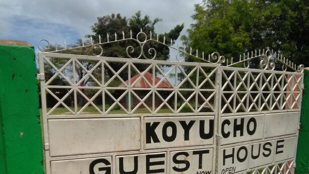 A gated entrance with the sign "KOYUCHO GUEST HOUSE" indicating it is open for guests. - Koyucho Guest House (Bondo)