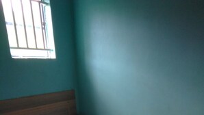 A bedroom with a bed, pillows, a window with bars, and a roll of toilet paper on a small table. - Koyucho Guest House (Bondo)
