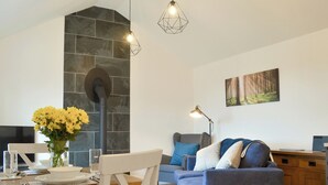 Uma sala de estar moderna com lareira de pedra, um sofá azul e uma área de jantar com mesa de madeira.