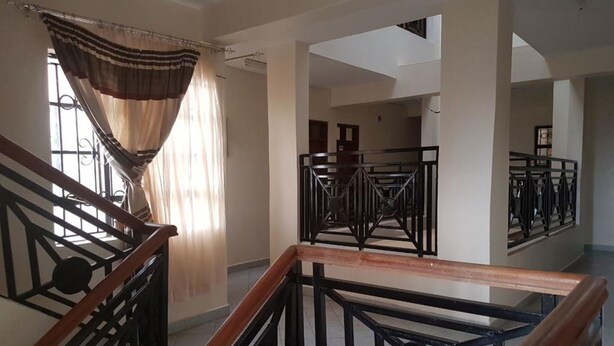 A spacious interior with a wooden staircase, a view of a balcony, and a large mirror reflecting the room.