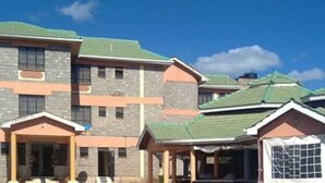 A residential building with a stone facade, multiple windows, and a green roof.