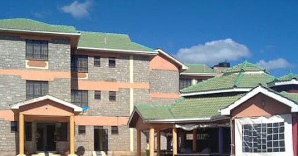 A residential building with a stone facade, multiple windows, and a green roof.