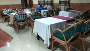 A dining area with multiple tables and wicker chairs.