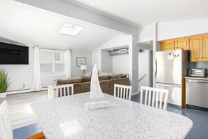 A modern kitchen with a central island, built-in appliances, and a dining area with a sailboat model.