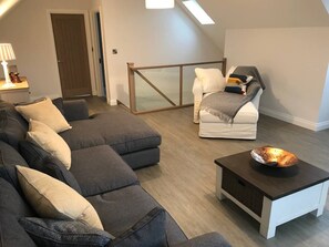 Una sala moderna con un sofá modular, un sillón blanco y una mesa de centro.