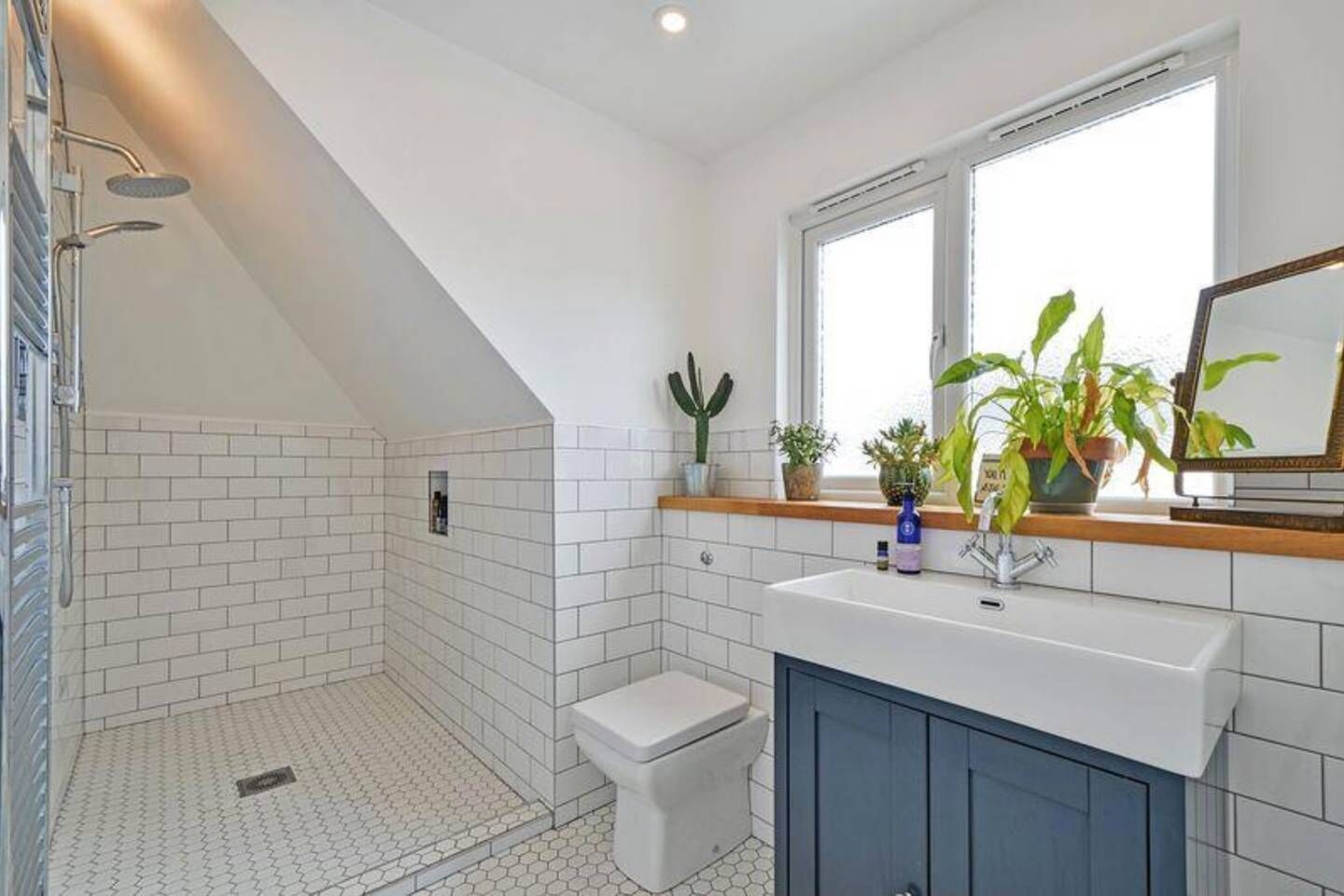 A bathroom with a shower, toilet, sink, and window.