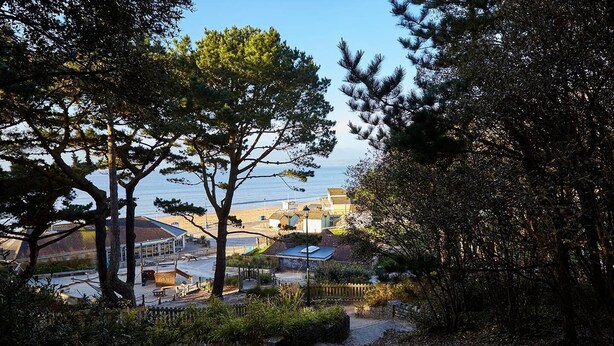 A coastal pathway with a view of a beach and buildings in the distance.