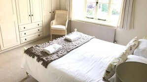 Une chambre à coucher avec un lit, une chaise, une fenêtre et une armoire.