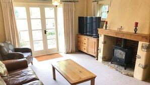 Un salon chaleureux avec un canapé en cuir, une table basse en bois, un téléviseur, une cheminée et un manteau de cheminée en pierre.