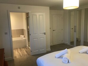 A hotel room with a bed, a bathroom with a bathtub, and a wardrobe. - New Home Near Science Park & City Centre (Exeter)