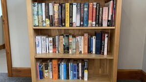 A wooden bookshelf filled with various books. - Abbey View Cottage - Scandi Spa Hot Tub (Chard)