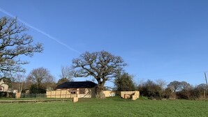 A rural property with a large tree, a house with a dark roof, and a fenced yard. - Abbey View Cottage - Scandi Spa Hot Tub (Chard)