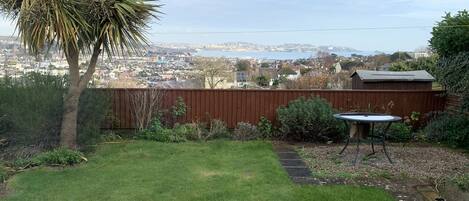A backyard with a wooden fence, a small table, and a lawn.