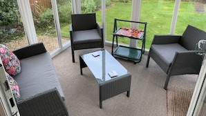 A sunlit patio with wicker furniture, a glass table, and a decorative tray. - Paignton View Holiday Home (Paignton)