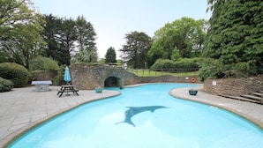 A swimming pool with a dolphin sculpture, stone walls, and a stone bridge. - Lakeview Cottage (Ivybridge)