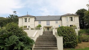 A large, two-story house with a central staircase leading to a front door. - Lakeview Cottage (Ivybridge)