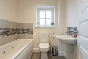 A modern bathroom with a bathtub, toilet, and sink.