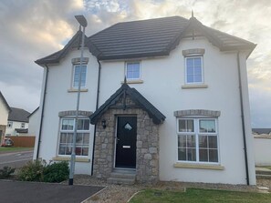A two-story house with a stone front, a black door, and a small porch. - Stylish & Modern 3 Bedroom Home (Bangor)