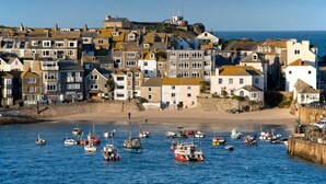 A coastal town with a harbor filled with boats, historic buildings, and a prominent lighthouse.