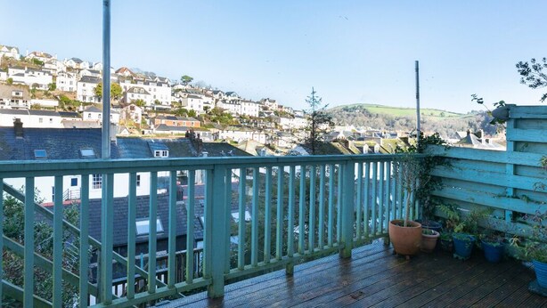 A wooden deck with a railing overlooking a residential area with houses and a hill in the distance. - Central Dartmouth Townhouse (Dartmouth)