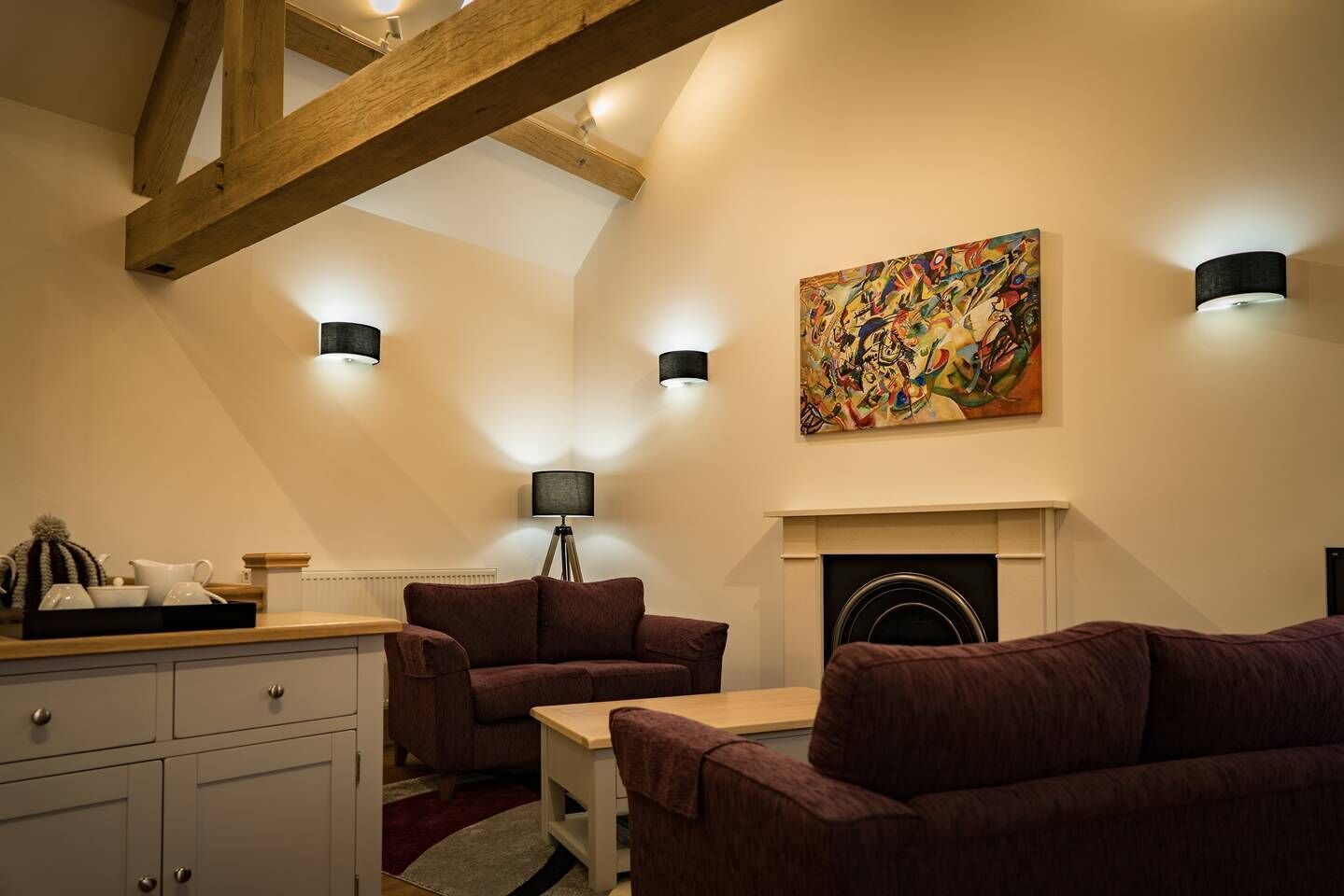 A cozy living room with a fireplace, a sofa, a coffee table, and a lamp.