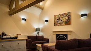 Ein gemütliches Wohnzimmer mit Kamin, einer Couch, einem Couchtisch und einer Lampe.