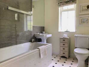 A bathroom with a bathtub, sink, toilet, and a window. - Bumble Bee Cottage (Tavistock)