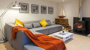 A modern living room with a grey sofa, yellow pillows, a white coffee table, and a wood-burning stove. - The Old Stable, Lower Parkstone, Poole (Poole)