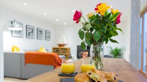 A dining table with a vase of flowers, two glasses of orange juice, and a pastry. - The Old Stable, Lower Parkstone, Poole (Poole)