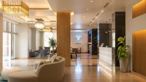 A modern lobby with a reception desk, seating area, and a large plant. - Citadines Al Ghubrah Muscat (Muscat)