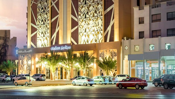 A modern hotel with a geometric facade and illuminated signage. - Citadines Al Ghubrah Muscat (Muscat)