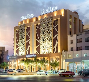 A modern hotel with a geometric facade and illuminated signage. - Citadines Al Ghubrah Muscat (Muscat)