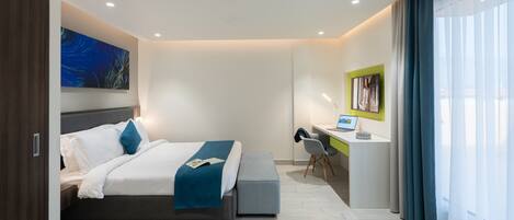Una habitación de hotel moderna con una cama grande, un escritorio y una computadora.