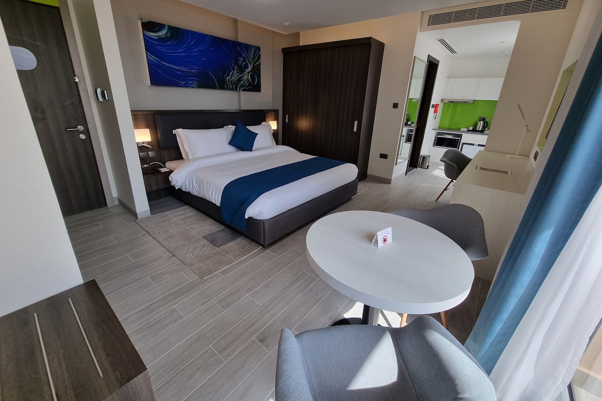 Una habitación de hotel moderna con una cama grande, una mesita y un espacio para sentarse.