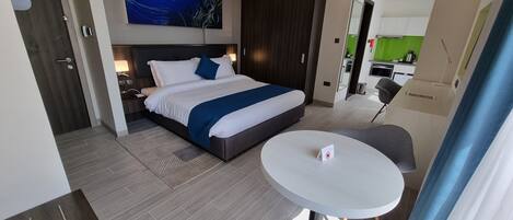 A modern hotel room with a large bed, a small table, and a seating area.