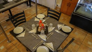 A dining table set for four with plates, cutlery, and condiments. - Maxoil Hotel (Nanyuki)