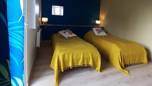 A room with two beds, a window, and a blue wall.
