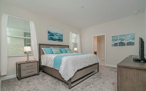Une chambre à coucher comprenant un lit, des tables de chevet, un bureau et des œuvres d’art accrochées aux murs.