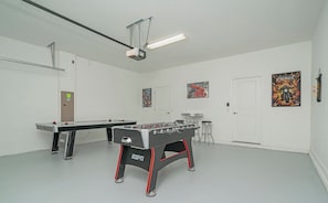 A room with a foosball table, a projector, and two doors. - Private Pool • Game Room • Waterpark • Golf • Gated Resort • Near Disney (Kissimmee)