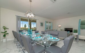 A modern dining room with a glass table, grey chairs, and teal accents. - Private Pool • Game Room • Waterpark • Golf • Gated Resort • Near Disney (Kissimmee)