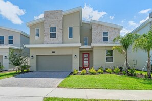 A two-story residential building with a red door, stone facade, and a well-maintained lawn.