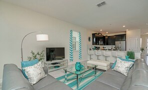A modern living room with a sofa, a glass coffee table, and a television. - Private Pool • Game Room • Waterpark • Golf • Gated Resort • Near Disney (Kissimmee)