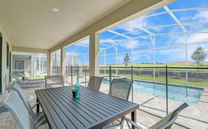 Un espacio al aire libre cubierto con piscina, mobiliario y vistas al paisaje.